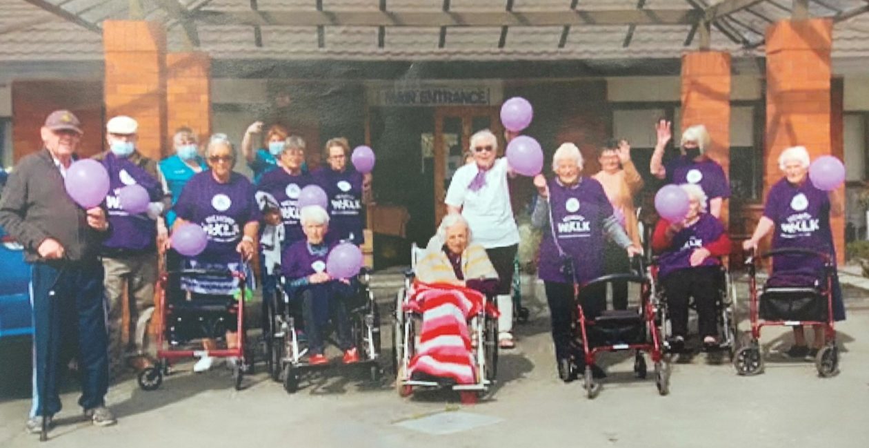 Residents and staff at Highfield Resthome gathered together posing for a photograph wearing alzheimers purple memory walk shirts