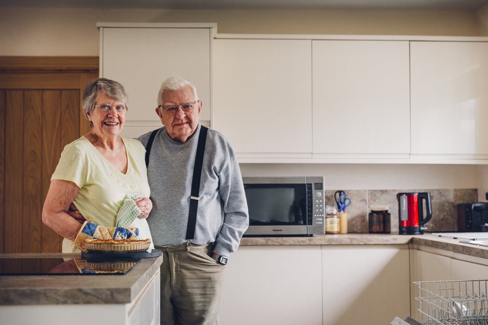 Couple standing in their kitchen smiling