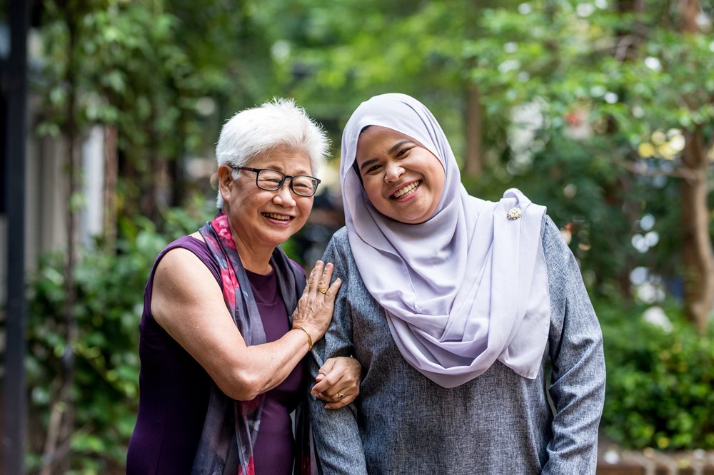 Two ladies of different ages and different cultures smiling.