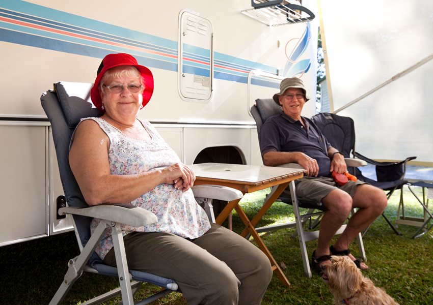 Couple sitting on camping chairs by their RV