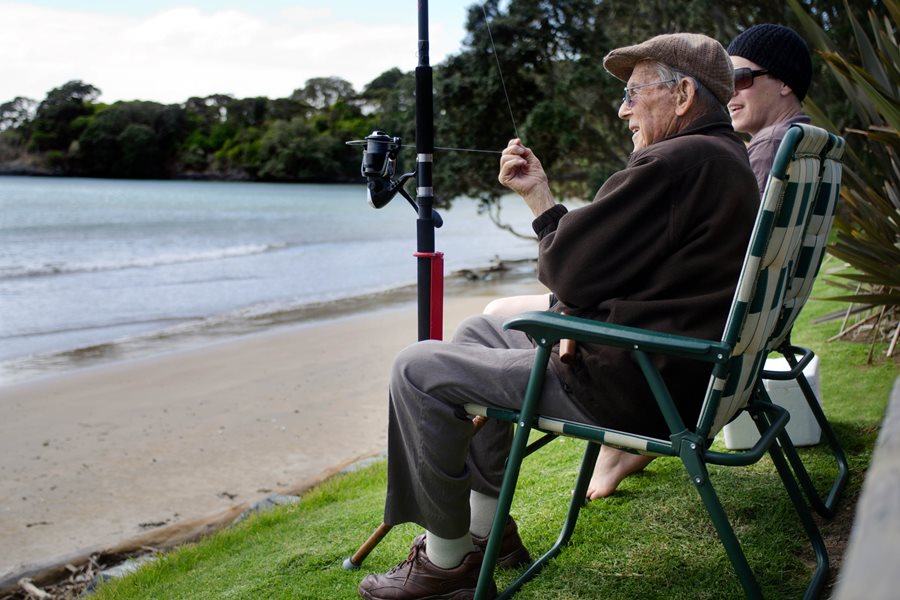 Two men sitting on the beach front fishing