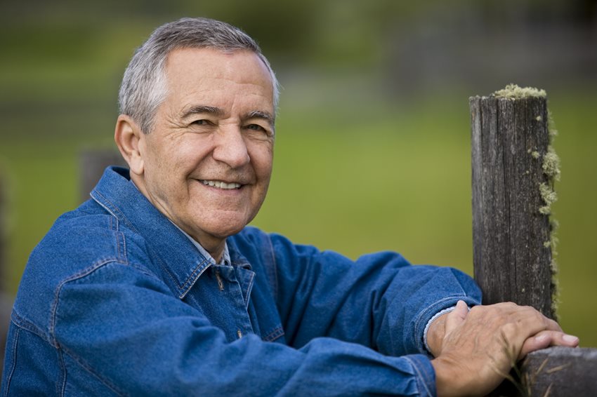 Man leaning on a fence and smiling