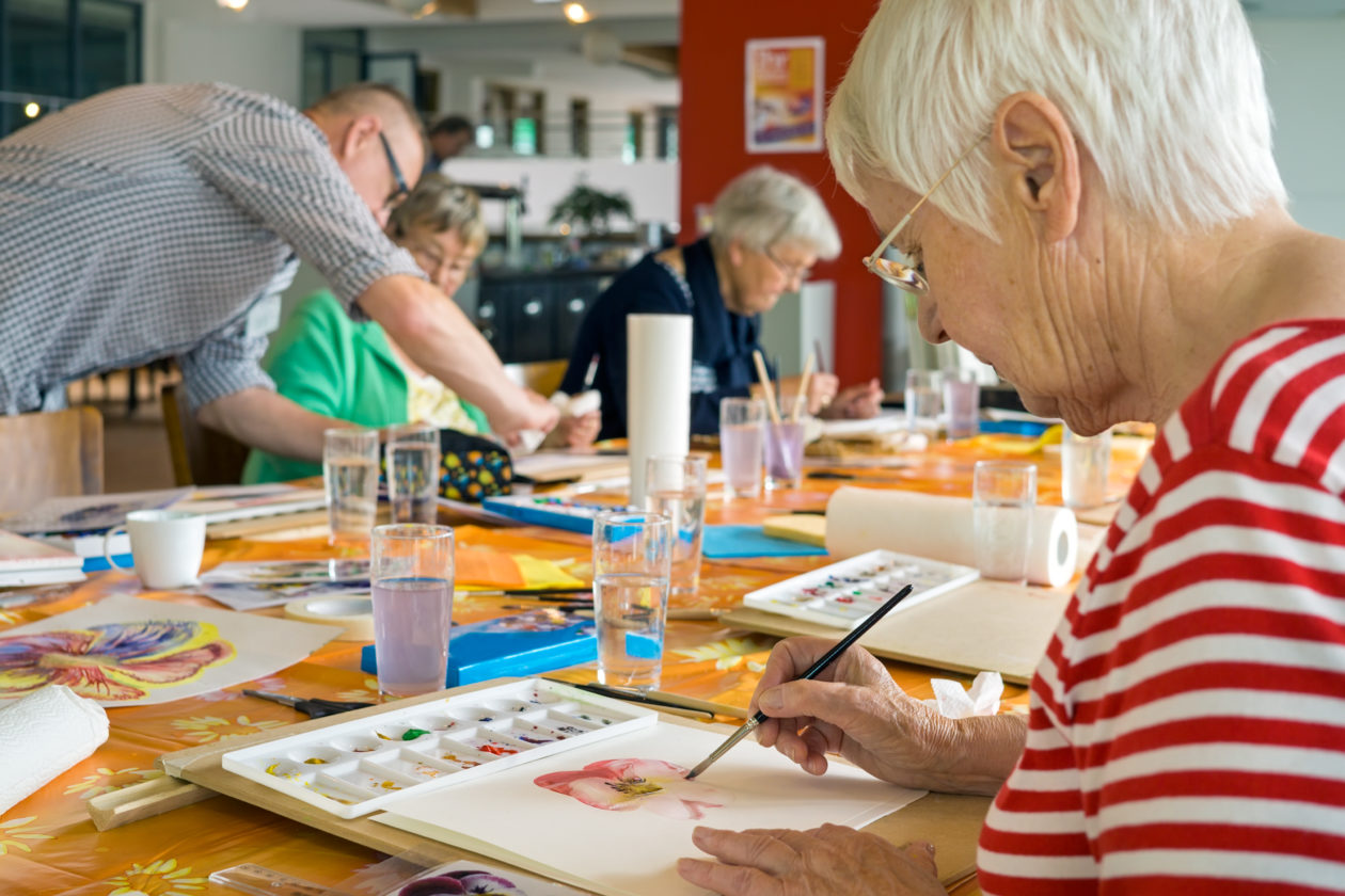 Older person sitting at a table painting with watercolours