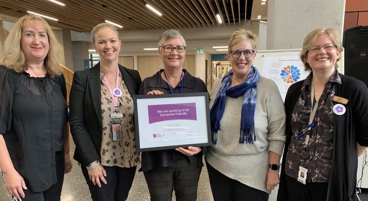 Group of people smiling and receiving the Dementia Friendly certificate