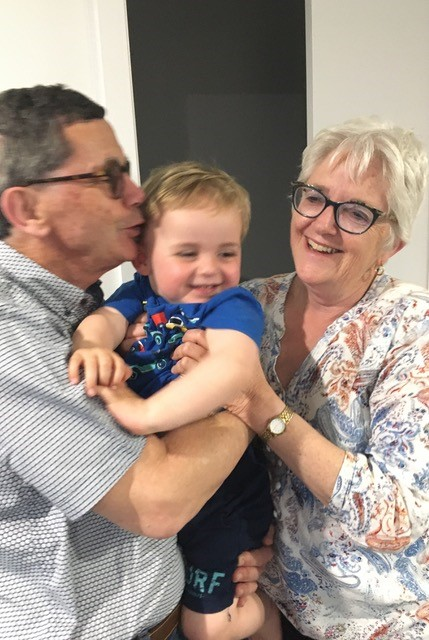 Andrew and Barbara holding their grandson Ethan and smiling