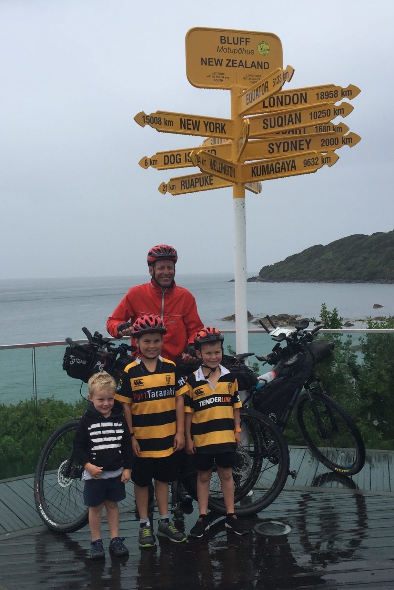 Mark at the Bluff viewpoint with his bike and his nephews smiling in the rain