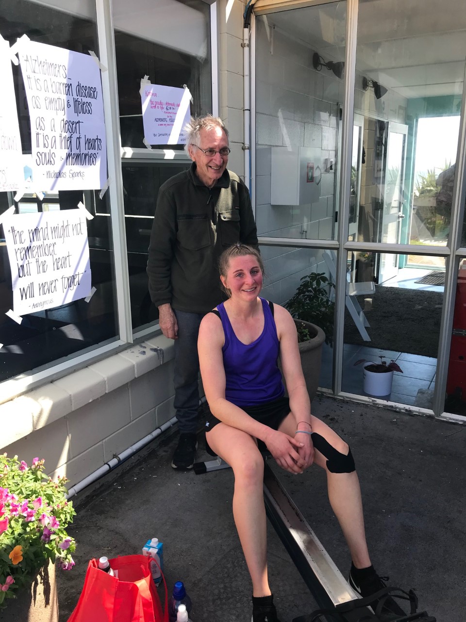 Katrina on the rowing machine with her Dad standing beside her