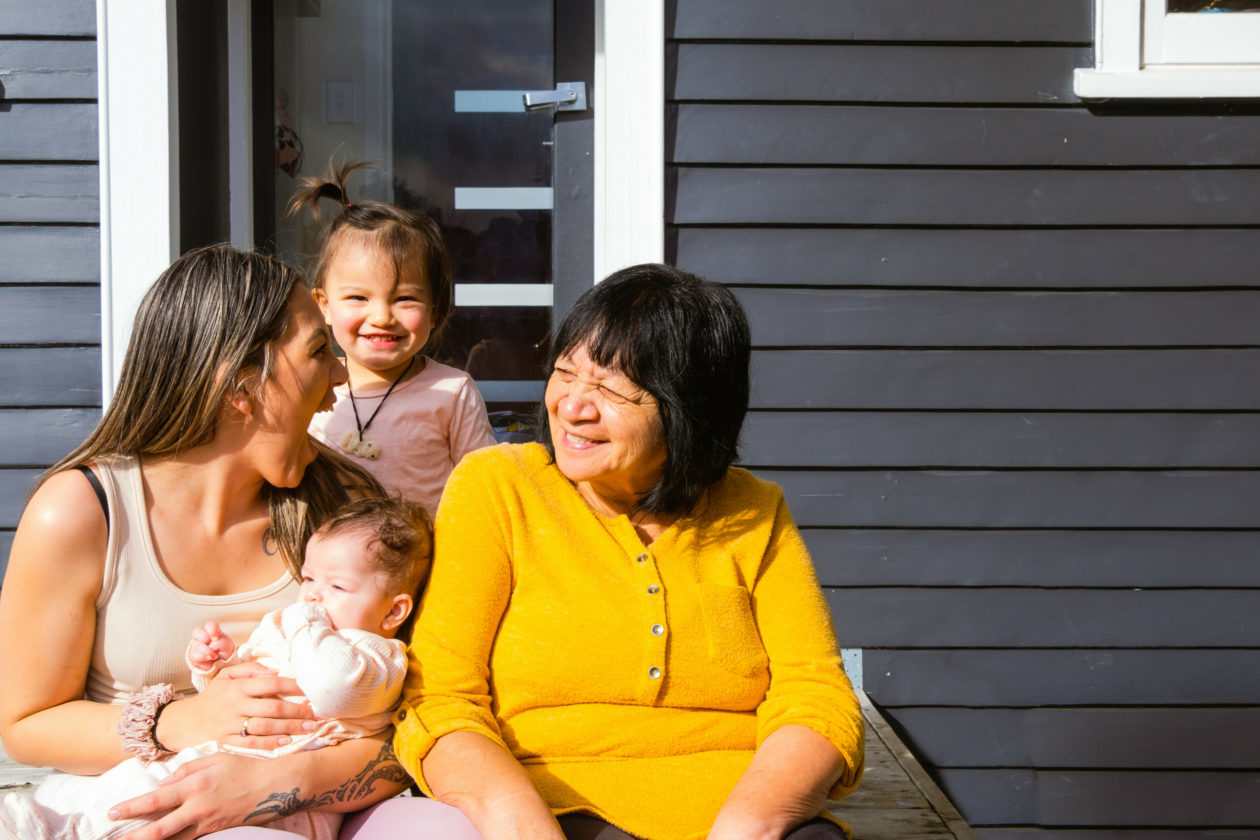 Whānau laughing on step - two women and two children